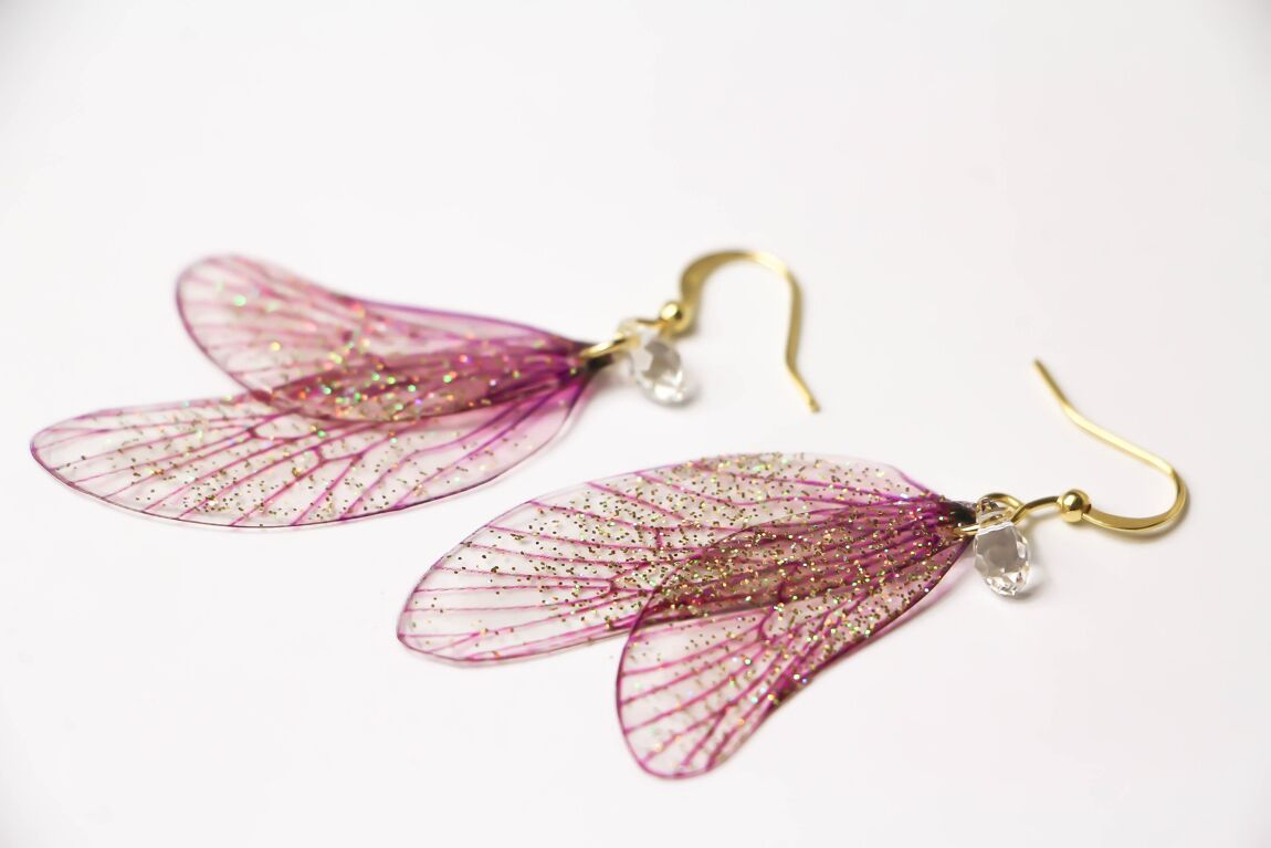 Magico paio di orecchini composto da due ali di fata in delicato rosa cipria, impreziosite da una leggera spolverata di glitter iridescenti