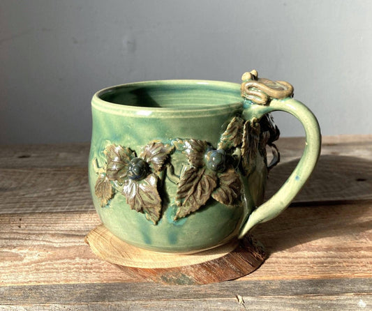 Tazza in ceramica con rana e decorazioni di more modellate a mano