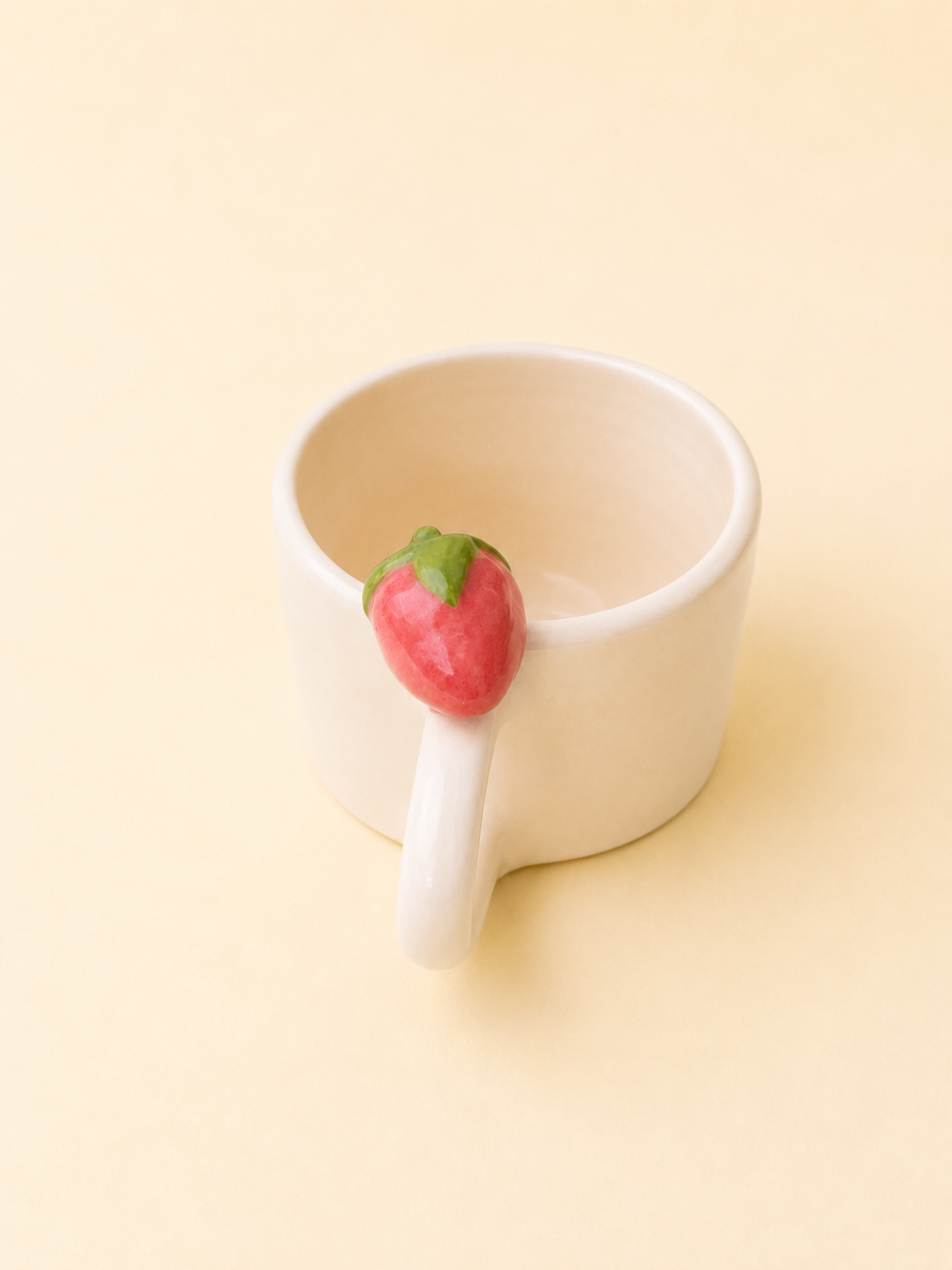 Tazzina da espresso color crema con piccola fragola rossa